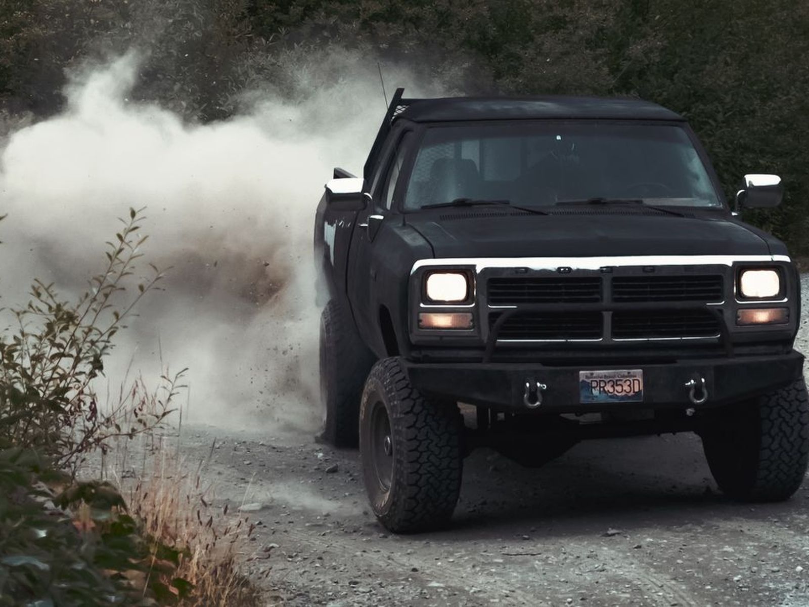 A dark pickup truck on a dusty back road